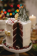 Cargar imagen en el visor de la galería, Pastel red velvet con betún de mantequilla y azúcar glass para 10 personas. La decoración incluye granada, galletas de mantequilla para las letras "X MAS" y mini pinitos navideños y piñitas de pino artificiales.
